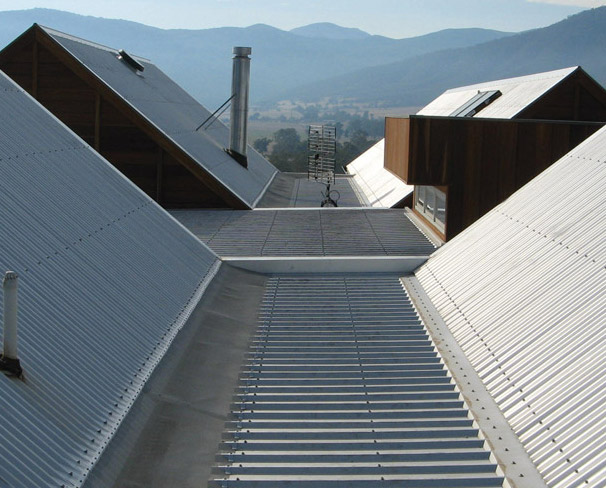 Roofing complex with gutters covered by gutter mesh gutter guards. Mountains and fields in the backgrounds