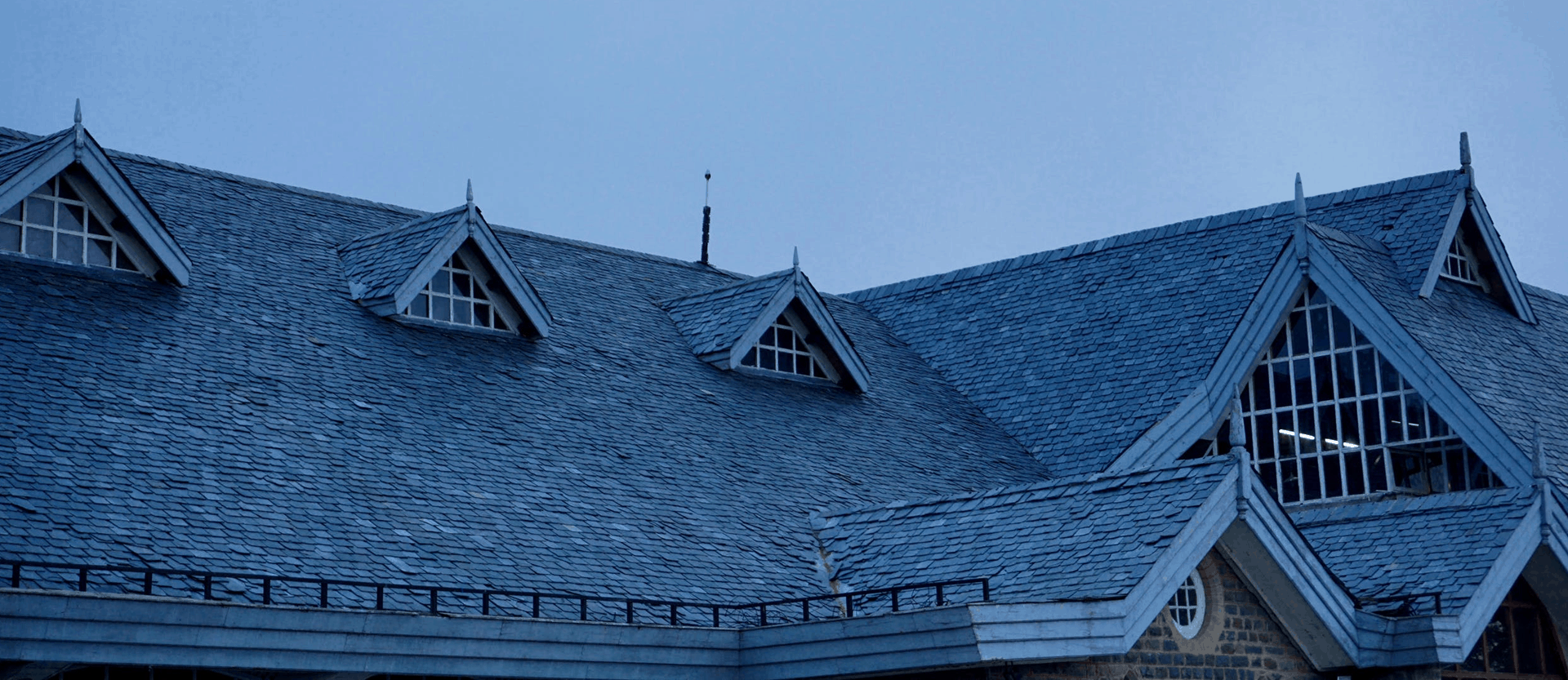 Photo of a large roof with shingles and gutter guards, taken at twilight