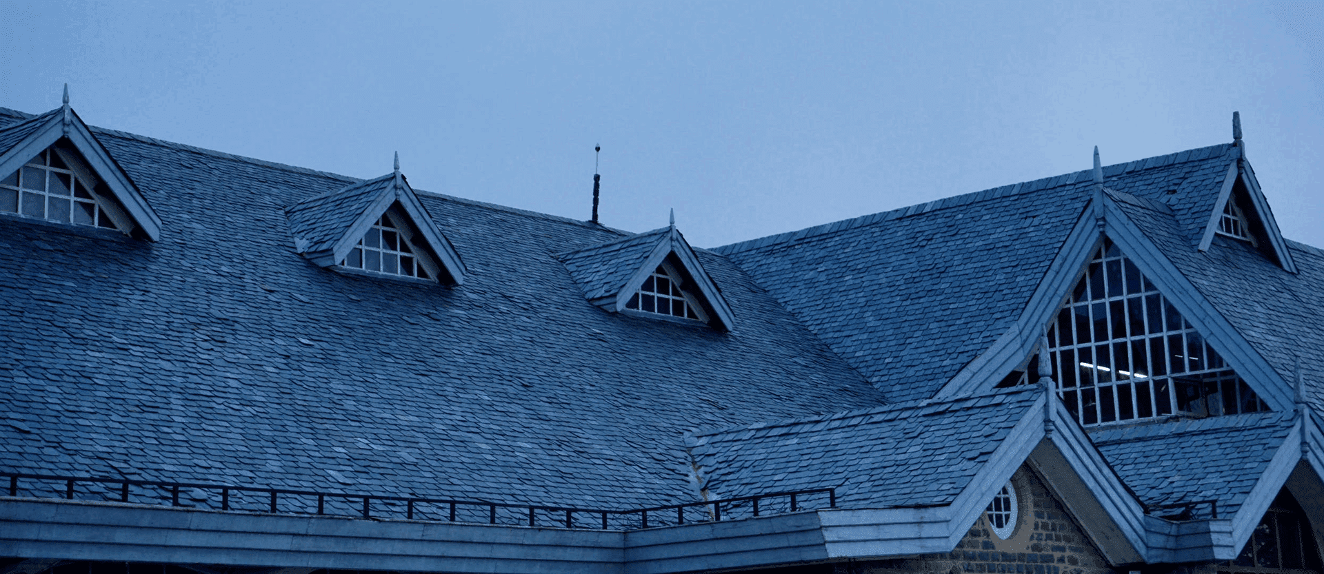 Photo of a large roof with shingles and gutter guards, taken at twilight