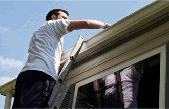 man on ladder cleaning gutters