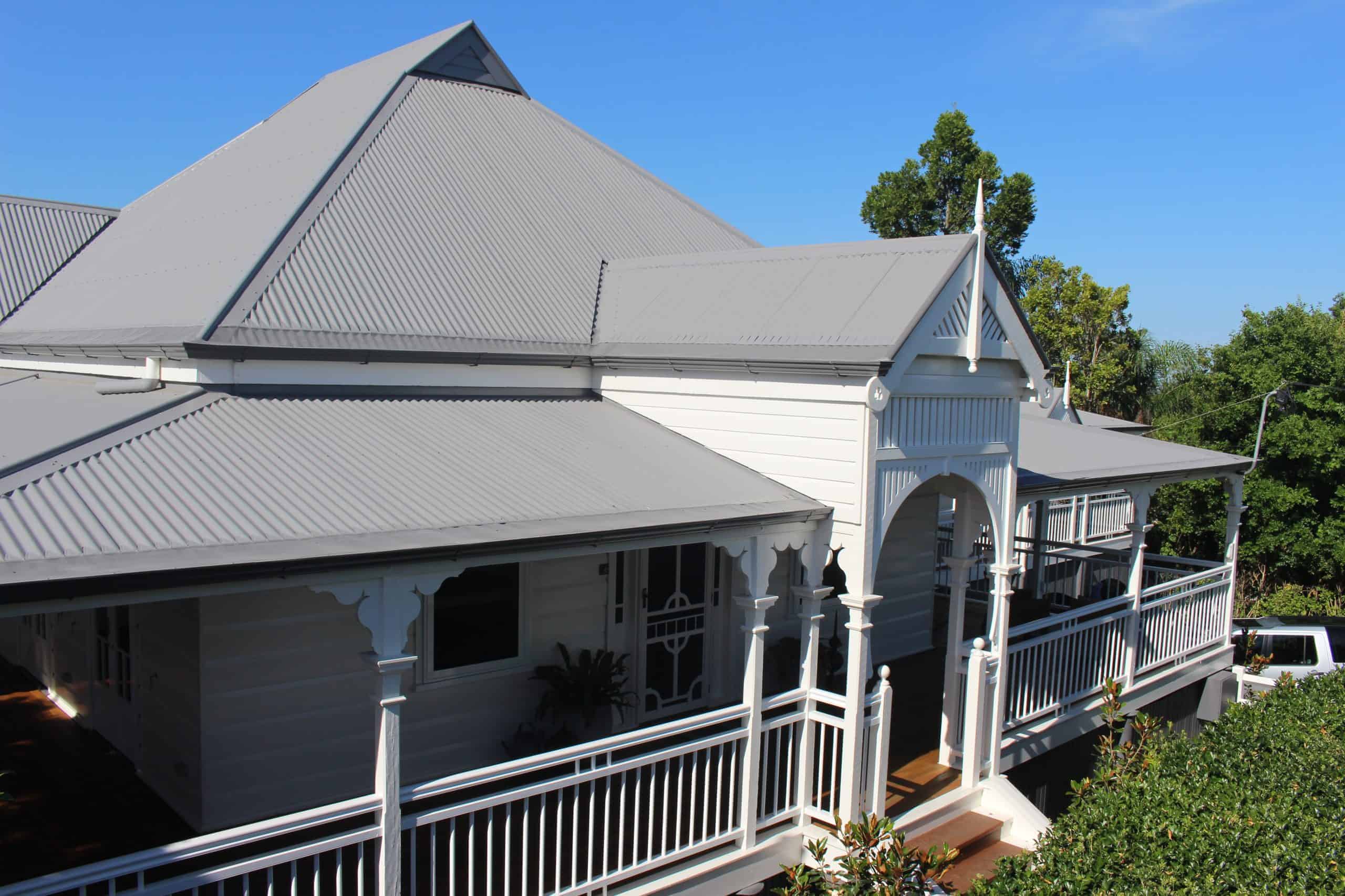White weatherboard house with grey metal roof and gutter guards.
